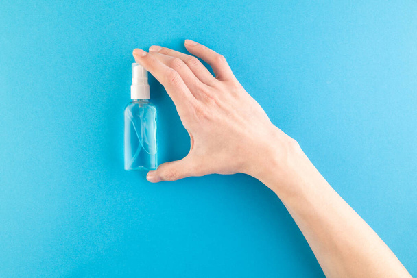 Hands hold a set of hygienic antiseptics and medications on a blue background. Antibacterial protection and self-care. Stop the spread of infection. Medical hygiene and virus protection concept. - Photo, Image