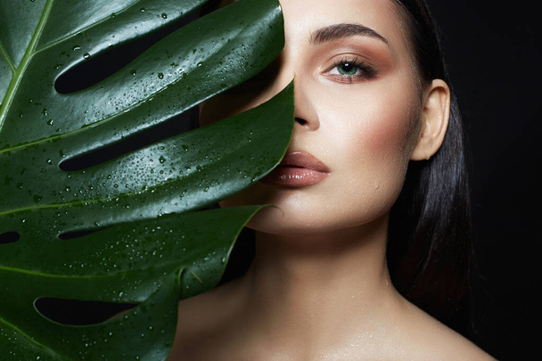 beautiful wet girl in palm leaves. Beautiful young woman with Make-up. Beauty Portrait. Natural cosmetics - Photo, Image