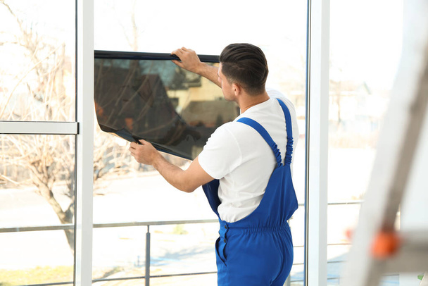 Professional worker tinting window with foil indoors - Φωτογραφία, εικόνα
