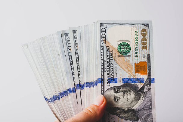 Veel biljetten van honderd dollar in de hand, op een lichte achtergrond, close-up. - Foto, afbeelding
