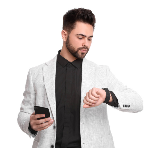 Young businessman with smartphone checking time on white background - Fotó, kép
