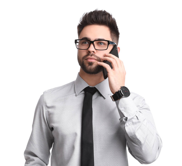 Young businessman talking on smartphone against white background - Foto, Imagen