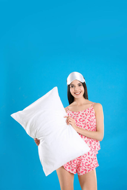 Young woman with pillow and sleep mask on blue background - Фото, зображення