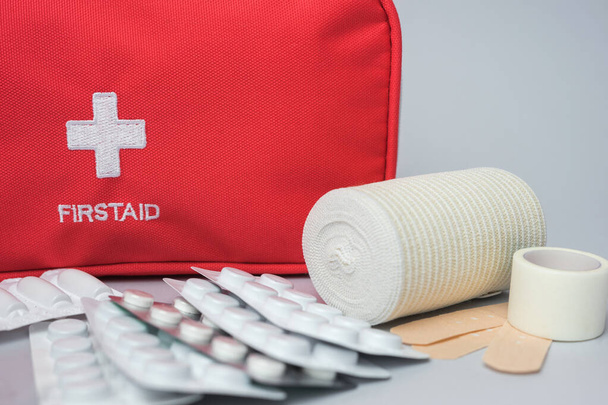 Orvosi elsősegély készlet gyógyszerrel és pirulákkal szürke alapon. Piros táska orvosi felszereléssel és gyógyszerekkel vészhelyzet esetére. Első látásra. Közelről.. - Fotó, kép