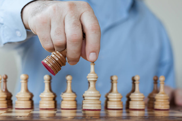 Strategy concept, hand of businessman moving wooden chess figure in play, management or leadership competition success background - Photo, Image