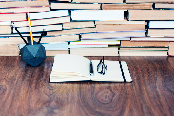 Cuaderno, lápices, vasos y pila de libros, antecedentes escolares para el concepto de aprendizaje educativo
 - Foto, Imagen