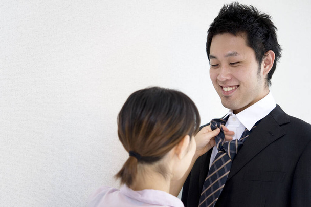 vrolijk aziatische vriendin koppelverkoop vriend stropdas geïsoleerd op wit achtergrond - Foto, afbeelding