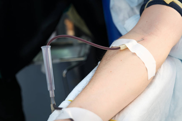Közelíts rá egy véradó emberre. A férfi donor vért ad egy mobil véradó központban. Adomány a coronavírus pandémia támogatásához, szelektív fókusz. A véradók világnapja - Fotó, kép