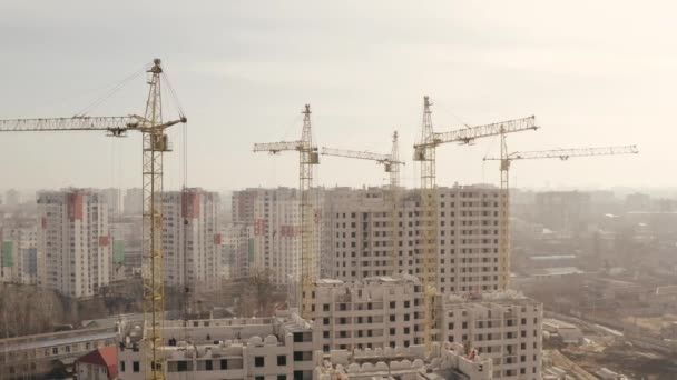 Strzał w wysokość kilka żółty budowlany suwnica i budowa nowy budowla dla budownictwo mieszkalny-biurowy w centrum Charków, Ukraina. Budowniczowie budują nowy wieżowiec, widok z góry. - Materiał filmowy, wideo