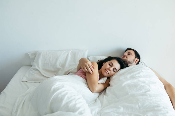 ζευγάρι κοιμάται στο κρεβάτι με λευκά σεντόνια αντίγραφο χώρο - Φωτογραφία, εικόνα