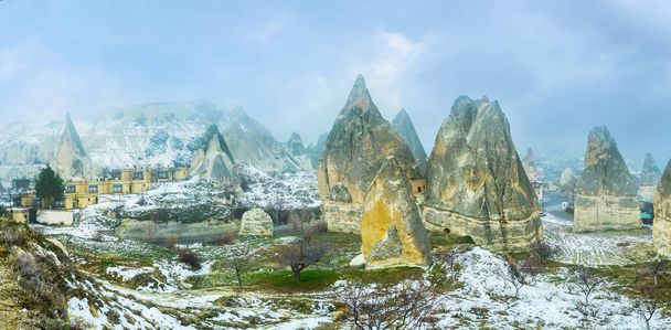 Panorama of huge yellow tuff rocks, surrounded by snowy lawn and located in large canyon next to Goreme, Cappadocia, Turkey - Fotó, kép