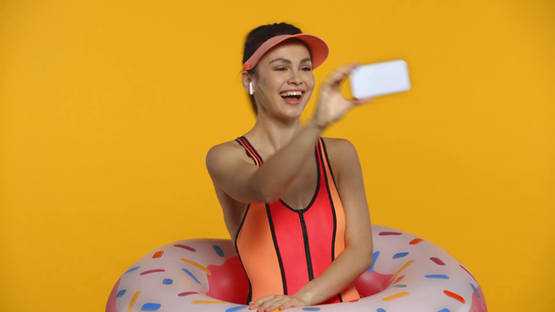 Улыбающаяся девушка в купальнике с видеозвонком на смартфон, изолированный на желтый
 - Кадры, видео
