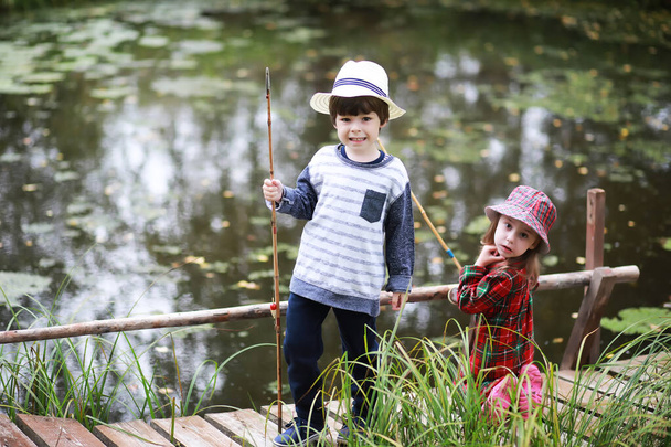 Jonge verkenners. Kinderen op een kampeertocht. Vissen om te vissen op een vijver en rivier. Grootmoeders vakantie in het dorp. - Foto, afbeelding