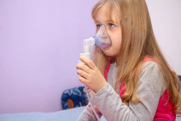 Kind mit Asthmaproblemen nimmt Inhalation mit Maske im Gesicht, Haustherapie. - Foto, Bild