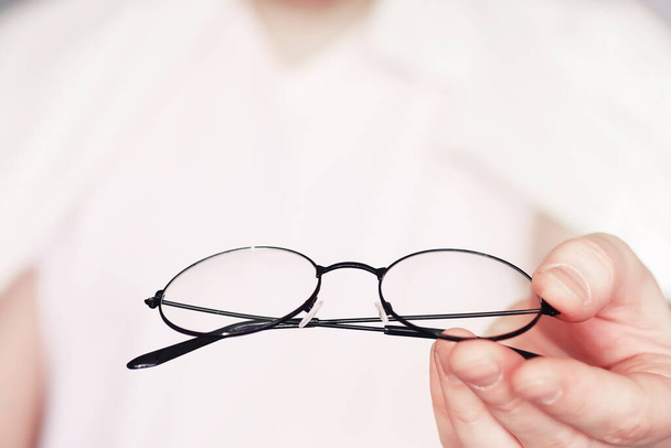 Das Konzept der Sehschwäche. Halten Sie eine Kontaktlinse und eine Brille in der Hand. Poster für Werbebrillen und -gläser. - Foto, Bild