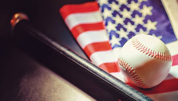 Amerikkalainen perinteinen urheilupeli. Baseballia. Konsepti. Baseball pallo ja lepakot pöydällä Amerikan lippu. - Valokuva, kuva