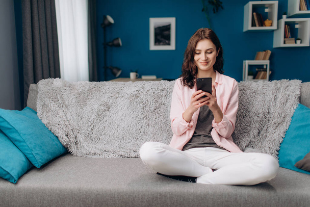 Attractive woman sitting on couch and using smartphone - Foto, immagini