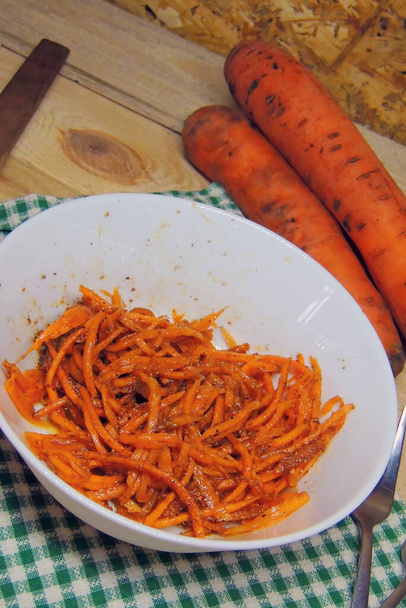 Ensalada de zanahoria caliente en tazón azul con tenedor sobre fondo marrón
 - Foto, Imagen