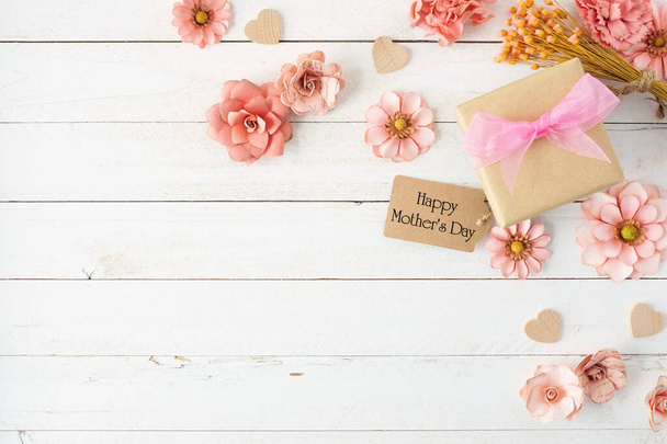 Happy Mothers Day Eckrand mit Papierblumen, Geschenkschachtel und Anhänger. Draufsicht über einen weißen Holzhintergrund. Kopierraum. - Foto, Bild