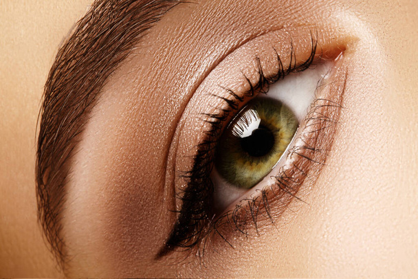 Schöne Makroaufnahme eines weiblichen Auges mit klassischem Eyeliner-Make-up. Perfekte Form von Augenbrauen, braunen Lidschatten und langen Wimpern. Kosmetik und Make-up. Nahaufnahme Makroaufnahme von Fashion Liner Augen Visage - Foto, Bild