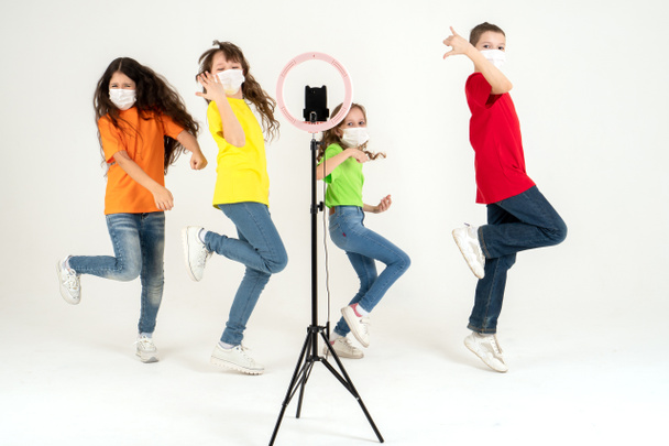 Dzieci tańczą pozytywnie w maskach medycznych. Koncepcja kształcenia na odległość podczas pandemii. Całkowicie. Ruch i sport. - Zdjęcie, obraz