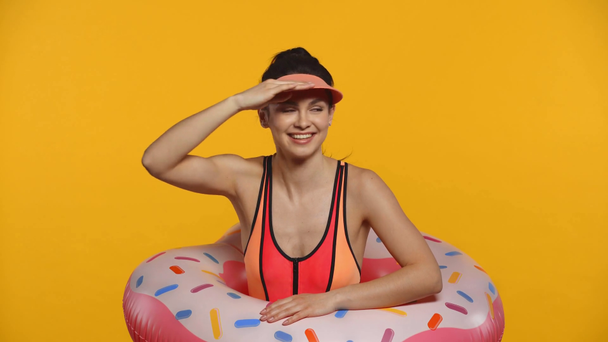 Cheerful girl in swimsuit and swim ring swimming isolated on yellow - Footage, Video