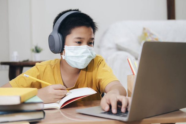 Αγόρι φορώντας μάσκες προσώπου online μελέτη homeshcooling στο σπίτι. - Φωτογραφία, εικόνα