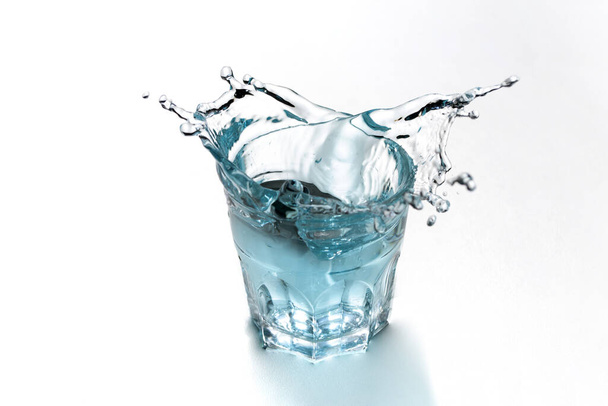 Sininen vesi roiskuu läpinäkyvässä lasissa. Virkistävä juoma
. - Valokuva, kuva