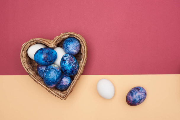 Beautiful festive Easter eggs in a basket on a colorful background. - Foto, afbeelding