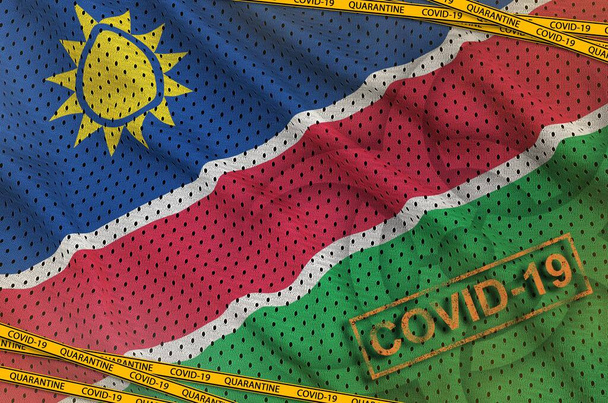 ナミビアの旗と隔離されたオレンジ色のテープとスタンプを持つCovid-19バイオハザードシンボル。コロナウイルスまたはパンデミック2019-nConvウイルスの概念 - 写真・画像