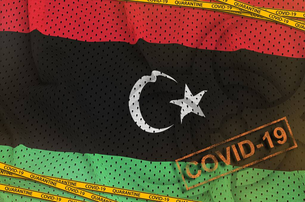 Bandera de Libia y símbolo de peligro biológico Covid-19 con cinta naranja de cuarentena y sello. Concepto de Coronavirus o pandemia 2019-nCov virus
 - Foto, imagen