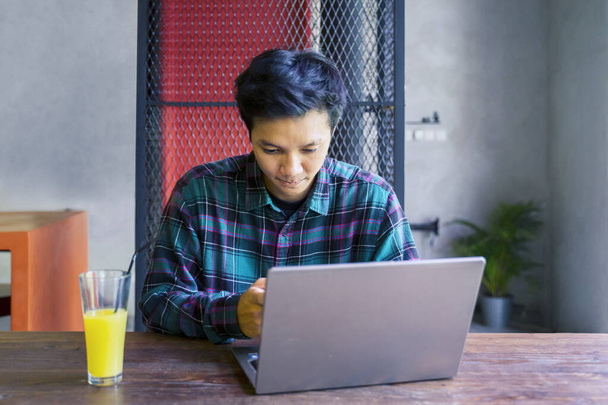 Portrait of young man using laptop while sitting in the restaurant with a glass of juice - Foto, Imagem