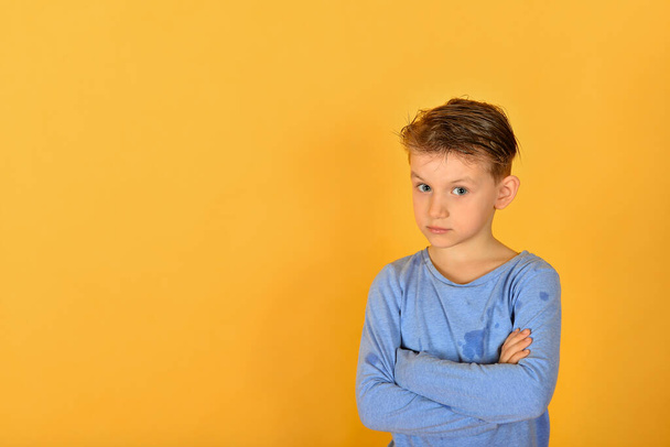 Гламурный и стильный мальчик позирует перед камерой, модель в синей одежде в студии на желтом фоне
. - Фото, изображение