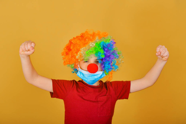 Un clown bambino con una maschera protettiva ti esorta a esaminare attentamente i segni del coronavirus.
. - Foto, immagini