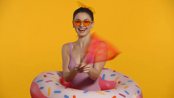 Χαμογελαστή κοπέλα με μαγιό και δαχτυλίδι κολύμβησης με δίχτυ εντόμων απομονωμένο στο κίτρινο - Πλάνα, βίντεο