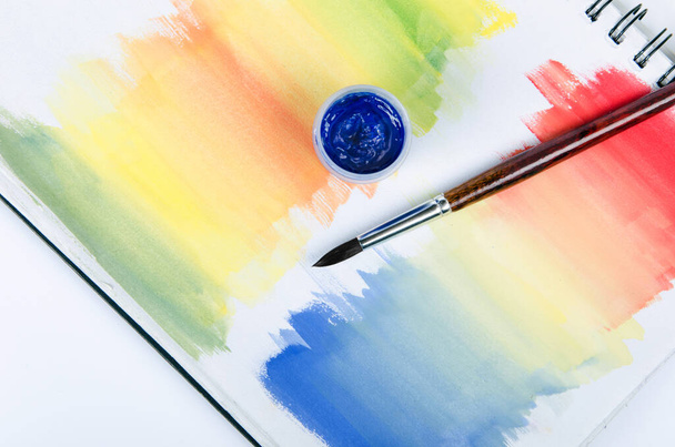 Μπουκαλάκια με χρώμα και πινέλο με χρωματιστό σημειωματάριο μονωμένα - Φωτογραφία, εικόνα