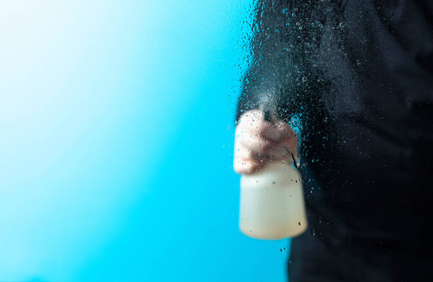 Mann in Gummihandschuhen sprüht Desinfektionsmittel auf ein Glas, selektiver Fokus. Kopierraum. - Foto, Bild