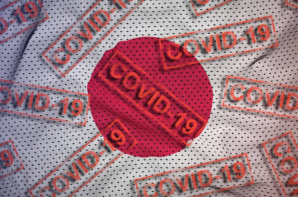 Ιαπωνική σημαία και πολλά κόκκινα γραμματόσημα Covid-19. Ιός του κερατοειδούς ή πανδημία έννοια του ιού 2019-nCov - Φωτογραφία, εικόνα