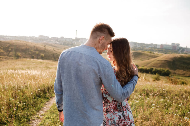 красивая молодая пара обнимается в поле с травой на закате. стильные мужчина и женщина весело проводят время на свежем воздухе. семейное понятие. копировальное пространство
 - Фото, изображение