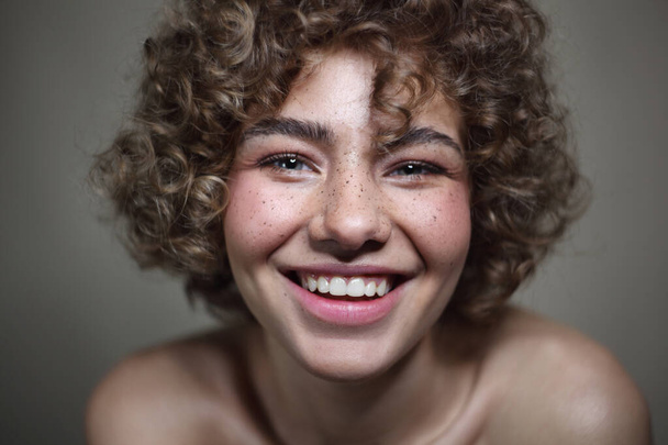 Vintage style portrait of smiling beautiful young freckled girl with curly hair, selective focus - Photo, image