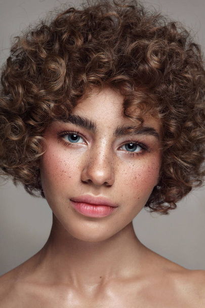 Portrait of young beautiful freckled girl with curly hair and clean makeup - Valokuva, kuva