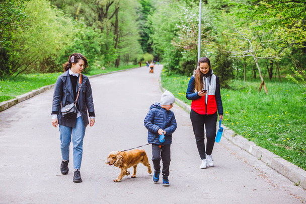 dvě ženy s malým dítětem a psem procházky v městském parku jarní sezóna - Fotografie, Obrázek