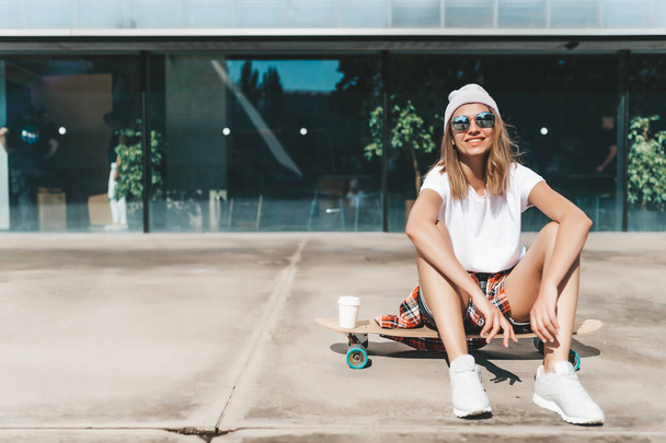 Attractive woman in sunglasses relaxing sitting on the longboard - Foto, immagini