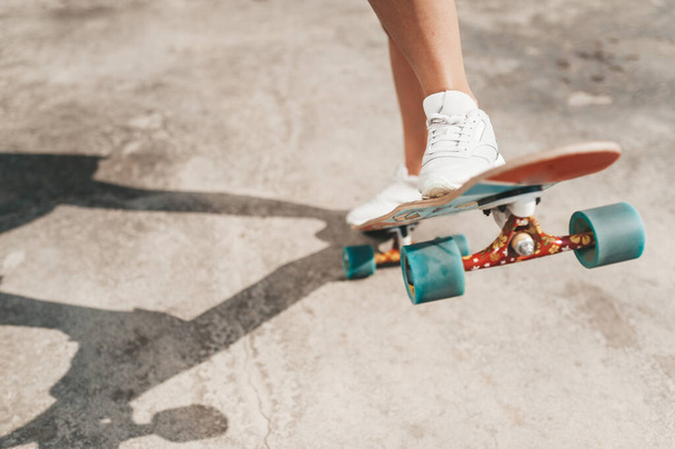 Close-up of female legs in sneakers on a longboard outdoors - Foto, Imagem