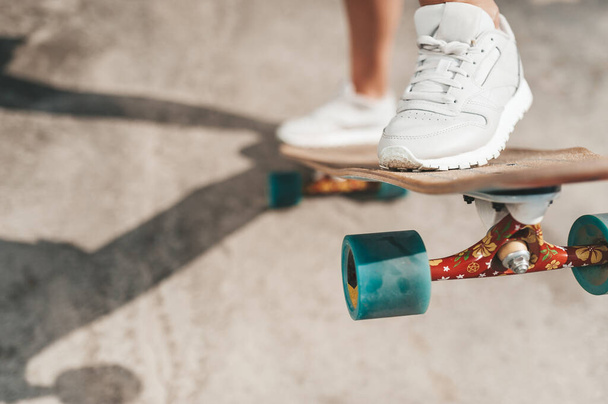 Close-up of female legs in sneakers on a longboard outdoors - Foto, immagini