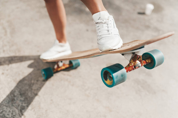 Close-up of female legs in sneakers on a longboard outdoors - Photo, Image