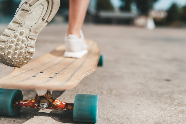 Close-up of female legs in sneakers on a longboard outdoors - Photo, image
