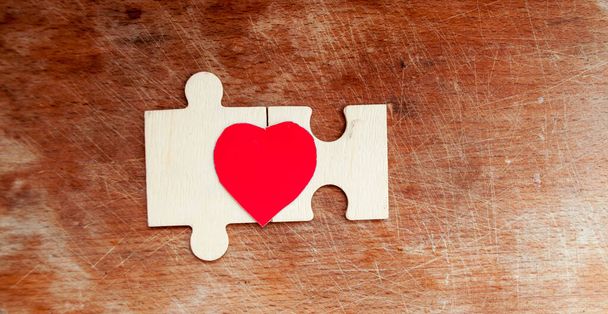木製の背景に赤い心を持つ2つのパズルピース。世界自閉症の日。4月2日 - 写真・画像