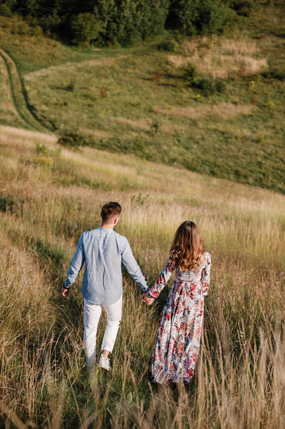 couple aimant se tenir la main et marcher dehors dans le champ. Concept d'amour et de famille. espace de copie. - Photo, image
