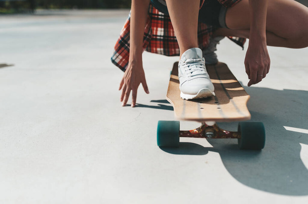 Close-up of female legs in sneakers on a longboard outdoors - Foto, Imagem